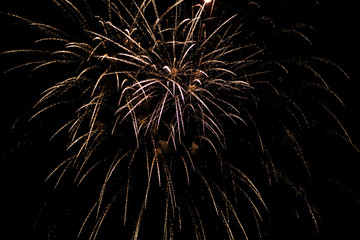 Fireworks in the sky. Salute exploded in a colorful ball in the night sky. Sparks and lights on a black background.