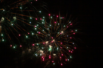 Fototapeta premium Fireworks in the sky. Salute exploded in a colorful ball in the night sky. Sparks and lights on a black background.