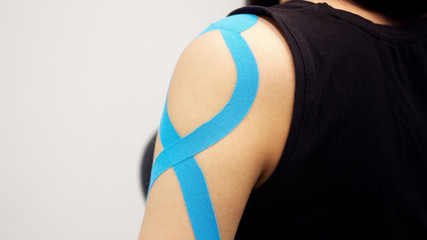 kinesiology taping treatment with blue tape on female patient injured arm. Sports injury kinesio treatment