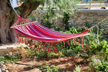 A red striped hammock hangs empty