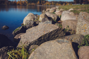 Fototapeta na wymiar large stones on the background of the river in the autumn park