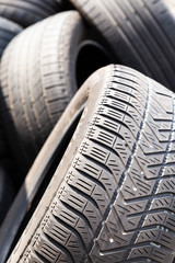 Close-up of used and old car tires with worn down treads randomly piled up in a stack © Andreas