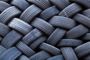 Close-up of a stack of old car tires with worn down profiles piled up in an interwoven pattern