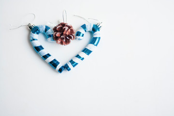 Christmas toys candy cane blue and white and a cone folded in the shape of a heart on a white background, copy space