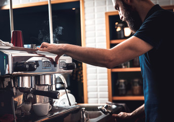 Barista preparing cappuccino on espresso machine for customer in coffee shop.