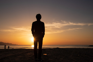 サンセットビーチに立つ男性の後ろ姿