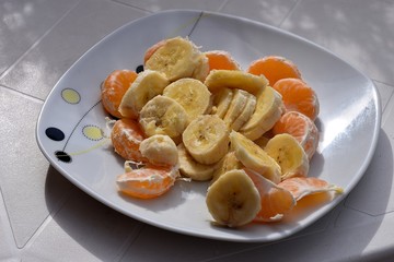 Plate full of sliced bananas and orange fruit/ Healthy breakfast and detox