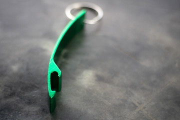 Naklejka premium The green bottle opener is placed on a gray cement floor.