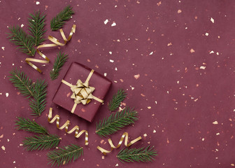 Christmas frame made of spruce branches, gold ribbons and gift box. Red paper background. New Year. Top view.