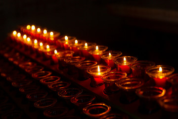 Burning candles in a temple in a row in the dark. Close-up. Background. Space for text.