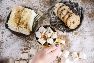 Hand holding mug on table with sweets