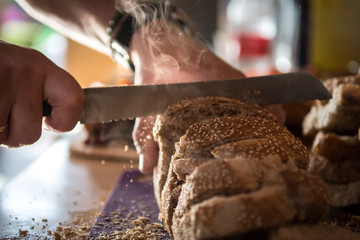 Isolated close up of a baker cutting a fresh steaming loaf of bread- Israel