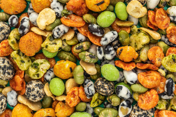 Background of Japanese snacks with peanuts, peas and wasabi, top view
