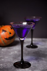 Two glasses with purple cocktail, pumpkin for Halloween party on the dark background