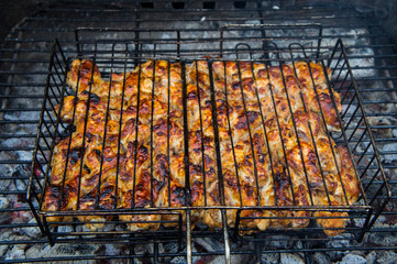 Grilled chicken meat on an iron grill barbecue grill closeup.