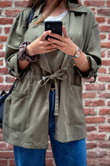 Close up of unrecognizable young female couple using smartphones in the street