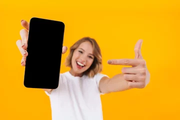 Foto op Plexiglas Image of young blond woman pointing finger at smartphone in hand © Drobot Dean