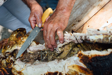 un homme découpe de la viande porc cuite au barbecue comme un boucher