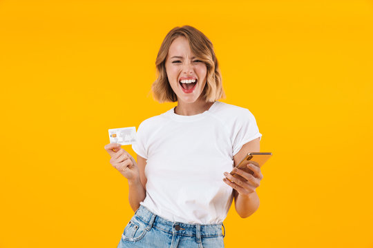 Image of cheerful blond woman holding smartphone and credit card