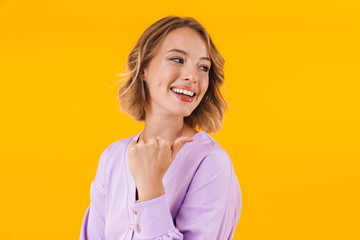 Fototapeta premium Image of woman in elegant dress smiling and pointing finger at copyspace