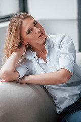 Obraz premium Resting and relaxation. Businesswoman with curly blonde hair sitting in room against window