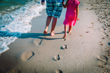 father and daughter walking on beach leaving footprint in sand