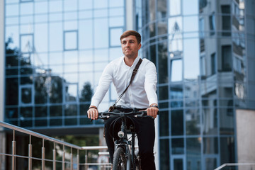 Professional politician. Businessman in formal clothes with black bicycle is in the city