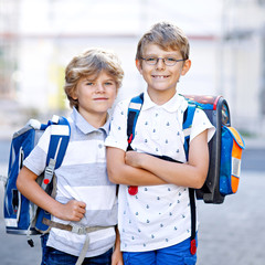 Two little kid boys with backpack or satchel. Schoolkids on the way to school. Healthy adorable...