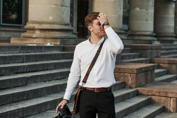 Obraz premium With expensive professional camera in hand. Photo of confident businessman in formal clothes in the city