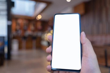 Man holding smartphone background with coffee shop.Blank screen mobile phone for graphic display montage.empty copy space for advertising.