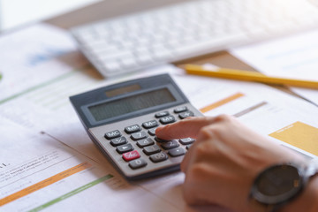 Close up hand of businesswoman or accountant working on calculator to calculate business data, and...
