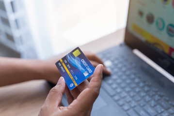 Man holding mock up banking card  while using and typing on laptop. Shopping and payment online.