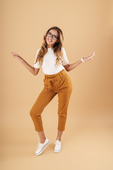 Full length image of young woman smiling and gesturing arms aside