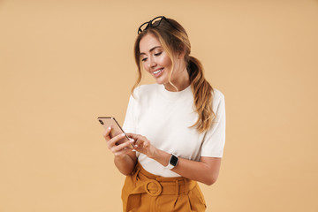 Image of charming young woman smiling and holding smartphone
