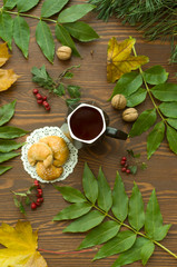  A cozy warm cup of delicious tea with homemade cookies on a wooden and foliage background