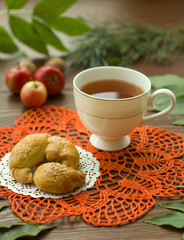  A cozy warm cup of delicious tea with homemade cookies on a wooden and foliage background