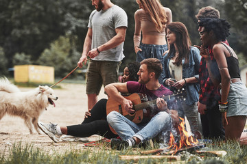 Noticed something in the woods. Group of people have picnic on the beach. Friends have fun at weekend time