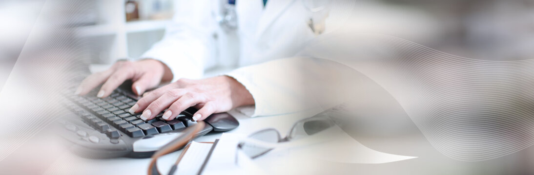 Female doctor taping on a computer keyboard; panoramic banner