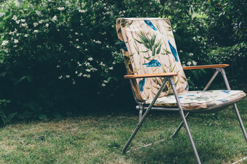 un fauteuil vintage dans un jardin. Un vieille chaise pliante dans un parc. Un fauteuil des années...