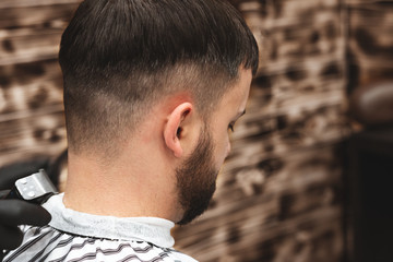 Obraz premium Haircut head in barbershop. Barber cuts the hair on the head of the client. The process of creating hairstyles for men. Barber shop. Selective focus.