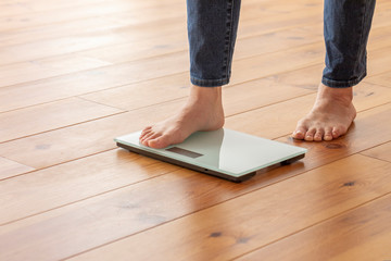 Fototapeta na wymiar 木目の床と体重計に乗る若い女性の足元