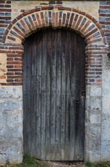 Fototapeta na wymiar Close up detail on side entrance wooden door of old castle in rural France