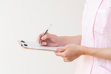 バインダーのメモに書き込む若い女性看護師