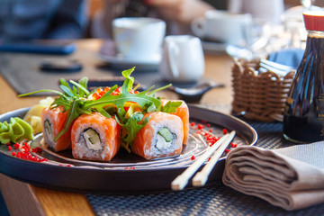 Sushi roll japanese food in restaurant. California Sushi roll set with salmon, vegetables, flying fish roe. Sushi with chopsticks. Japan restaurant menu cuisine