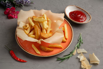french fries in an orange plate and tomato sauce in a cup