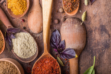 Heaps of various ground spices in wooden spoons on wooden background. Georgian spices, Indian spices, Arabian spices. Spice variety. Herbs and spices