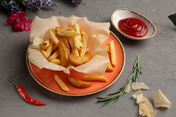 french fries in an orange plate and tomato sauce in a cup