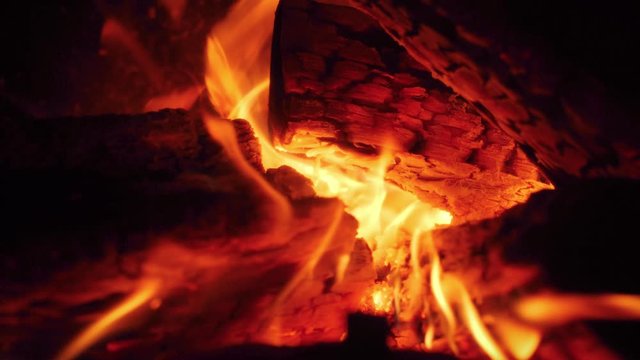 Macro slow motion video of fire flames slowly flowing from burning wooden logs in the oven