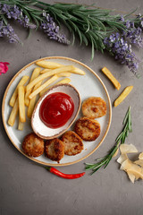 french fries, meat cutlets and ketchup in a white plate