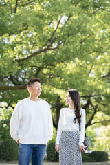 Fototapeta premium 綺麗な緑を背景に仲良く歩く若い男女